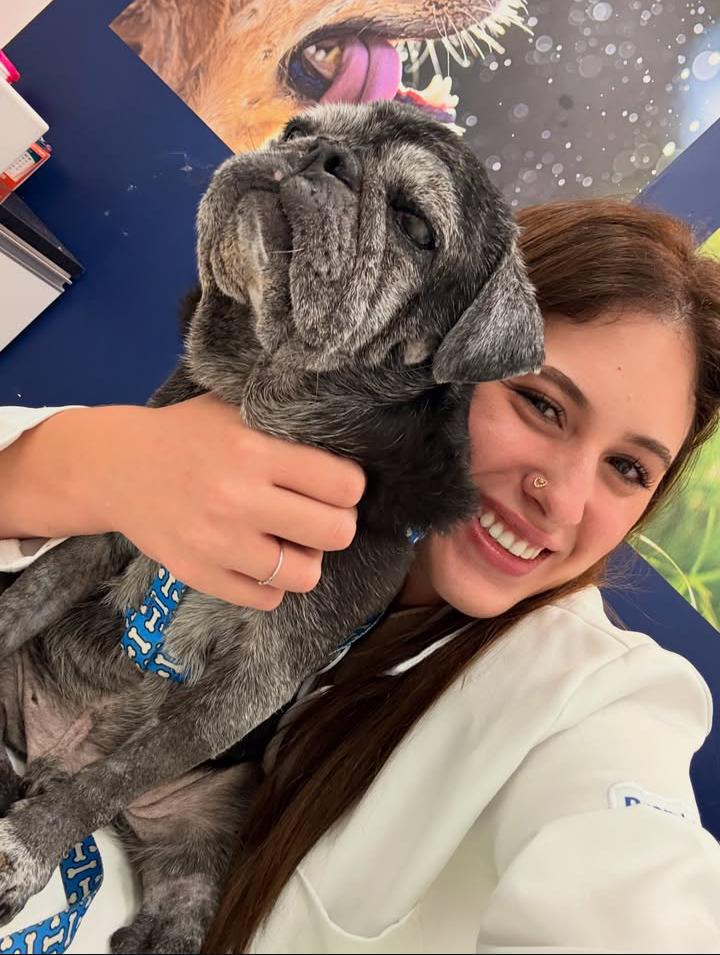 Dra. Jéssica Garofalo abraçando um cão de pequeno porte, sorrindo durante uma consulta.