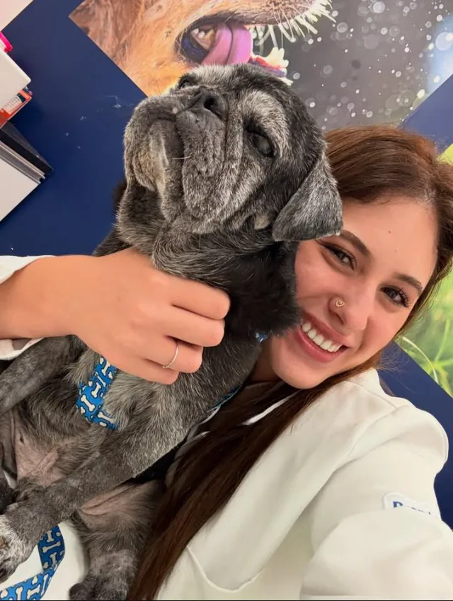 Dra. Jéssica Garofalo abraçando um cão de pequeno porte, sorrindo durante uma consulta.